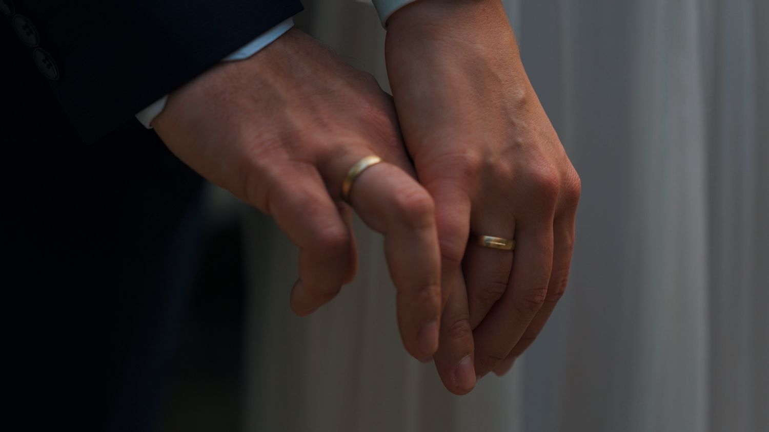 Close-up of hands exchanging wedding rings during ceremony.