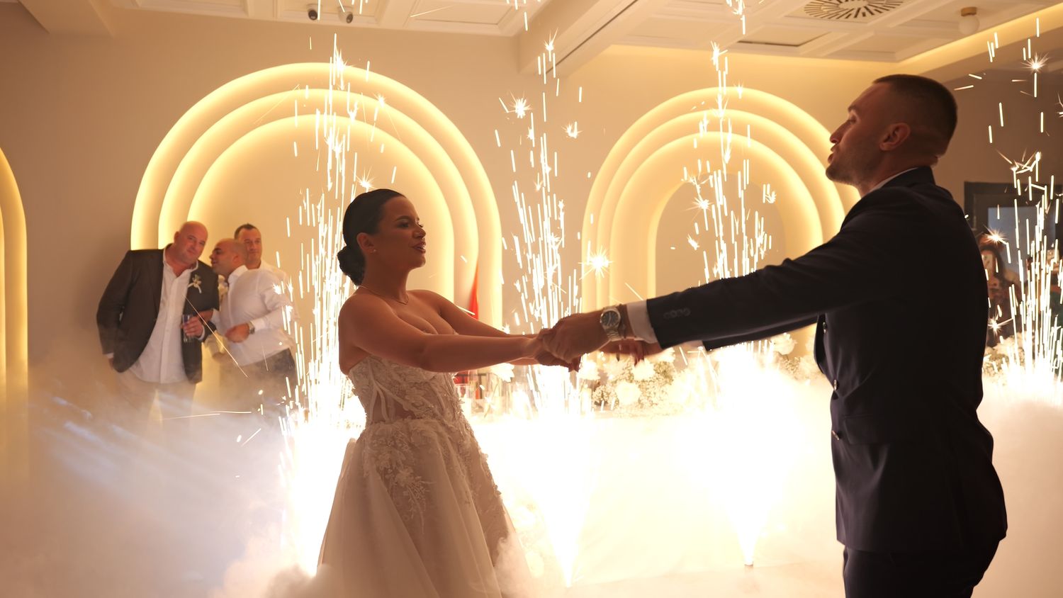 Newlyweds share their first dance surrounded by sparklers and illuminated arches at an elegant wedding reception.