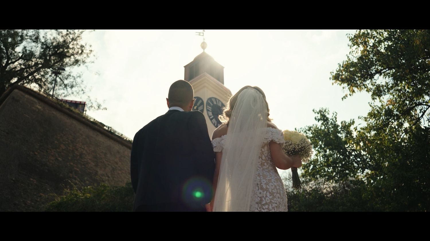 Romantic outdoor wedding photography with natural sunlight filtering through trees.