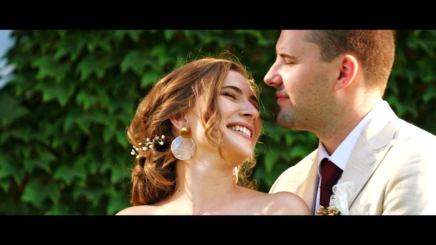 A tender moment captured between a couple against a green backdrop.