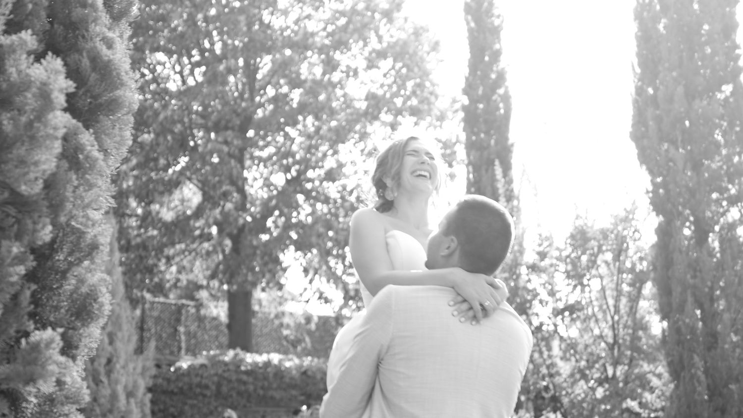Elegant black and white wedding photo with cypress trees in background.