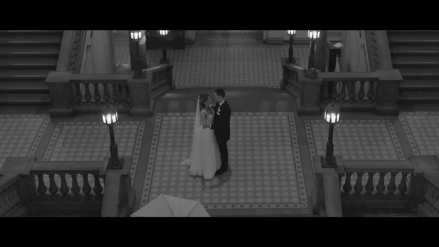 Elegant couple descending wide stone steps at historic building.