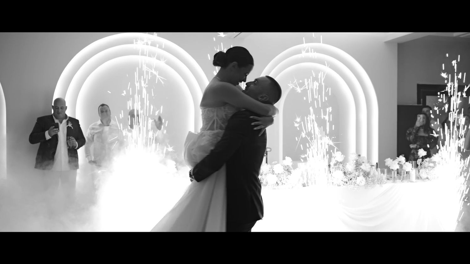 Dramatic black and white wedding ceremony scene with backlit archway.