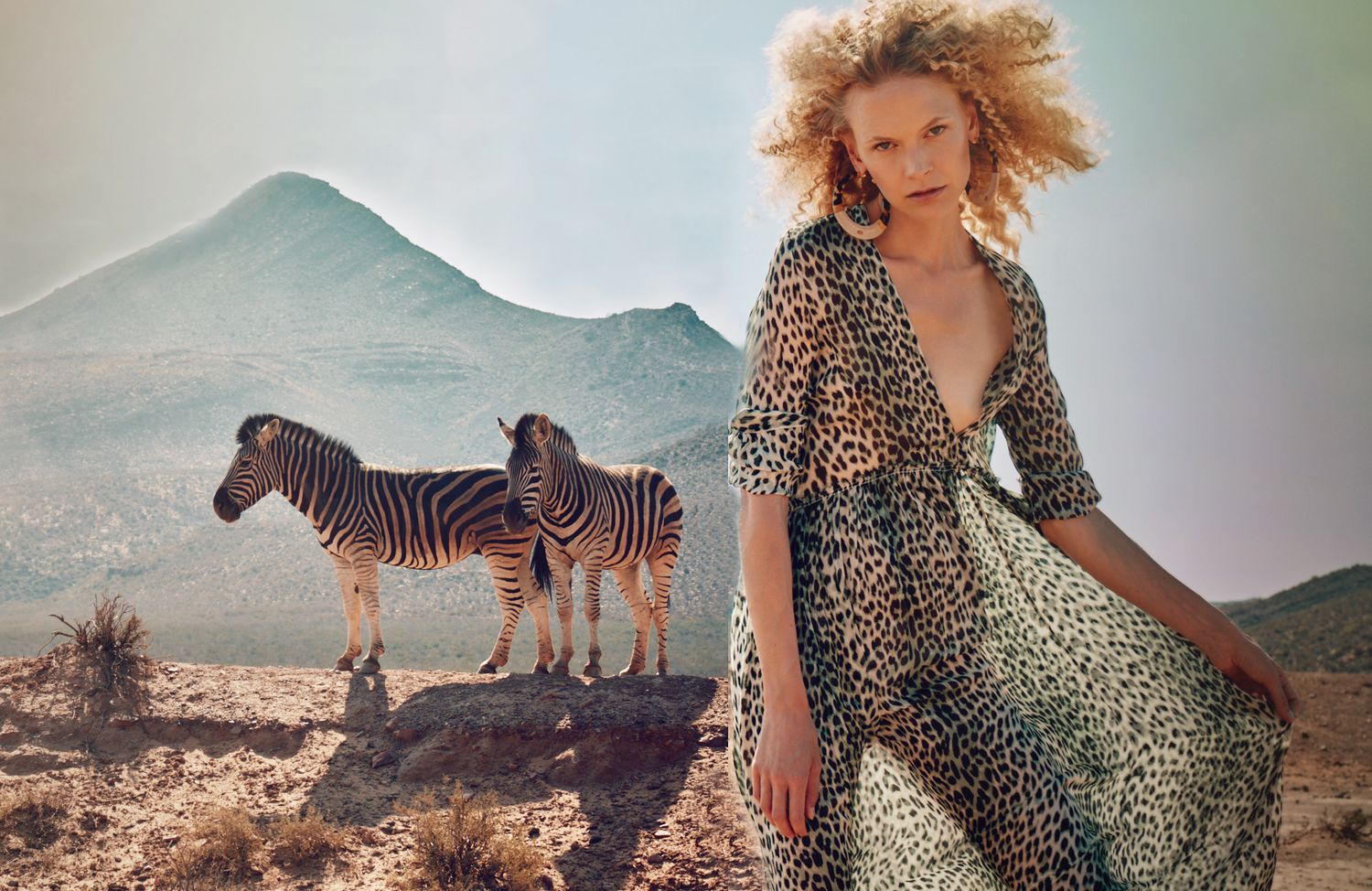Safari fashion shoot featuring leopard print dress with zebras and elephants in natural landscape.