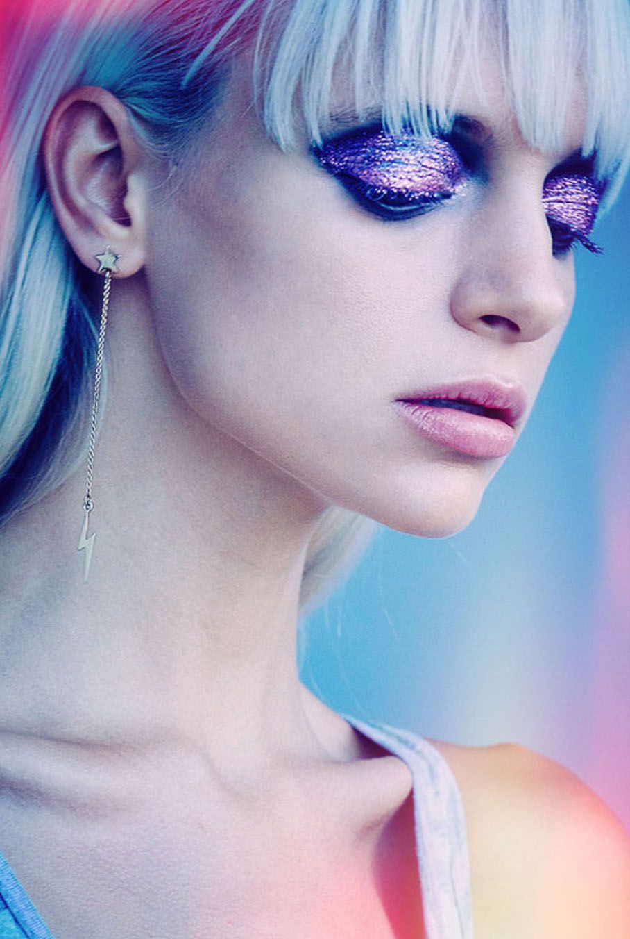 Close-up beauty shots with vibrant pink and blue lighting effects and glittery makeup.