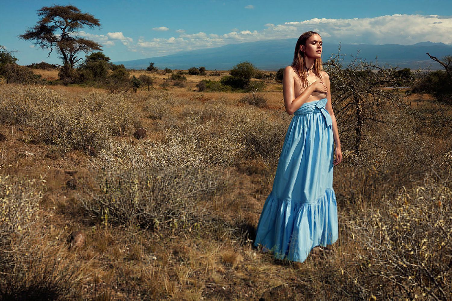Light blue sundress flows in desert breeze against rugged mountain backdrop.