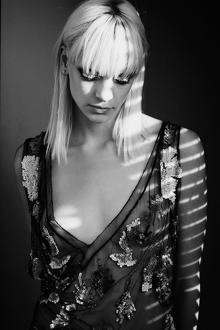 A dramatic black and white portrait series showing a figure in a sequined dress with light streaming through window blinds.