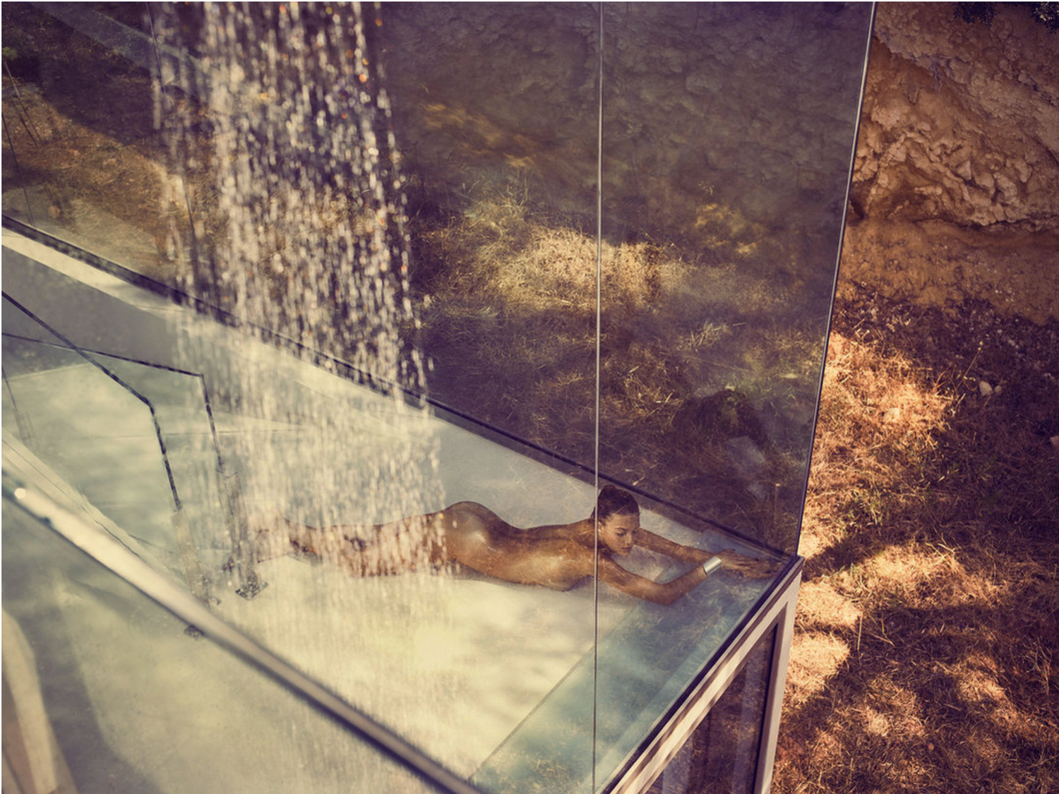 Water cascades from ceiling fixtures in luxury spa setting.