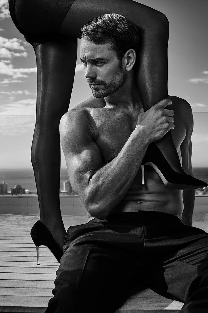 Artistic black and white beach photography featuring intimate couple poses on wooden deck.