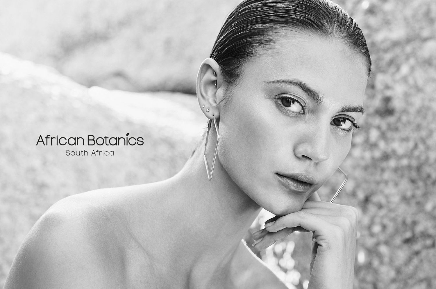 Dramatic black and white beauty portrait against textured stone background.