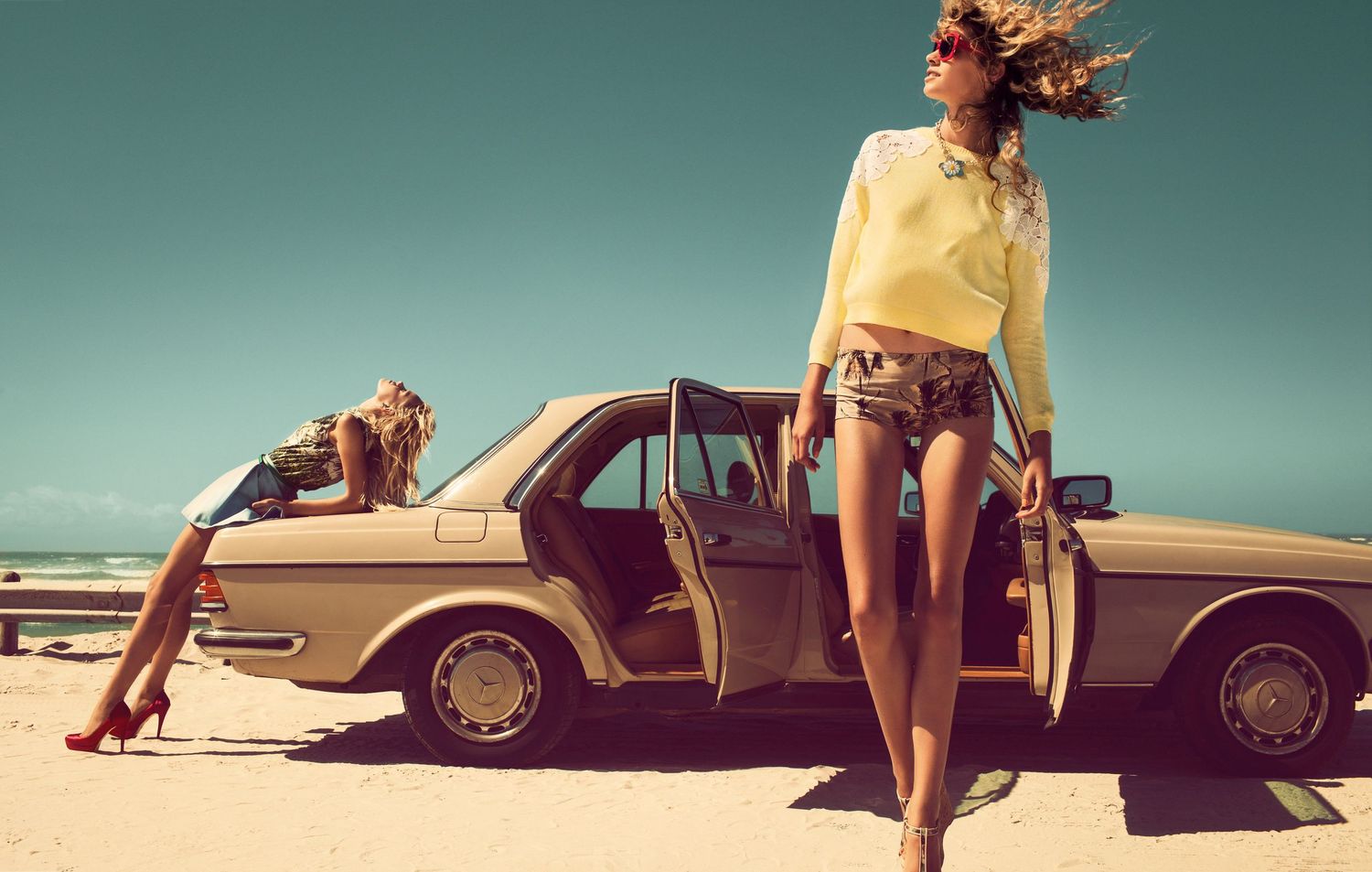 Vintage-style fashion shoot featuring a classic car in desert setting.