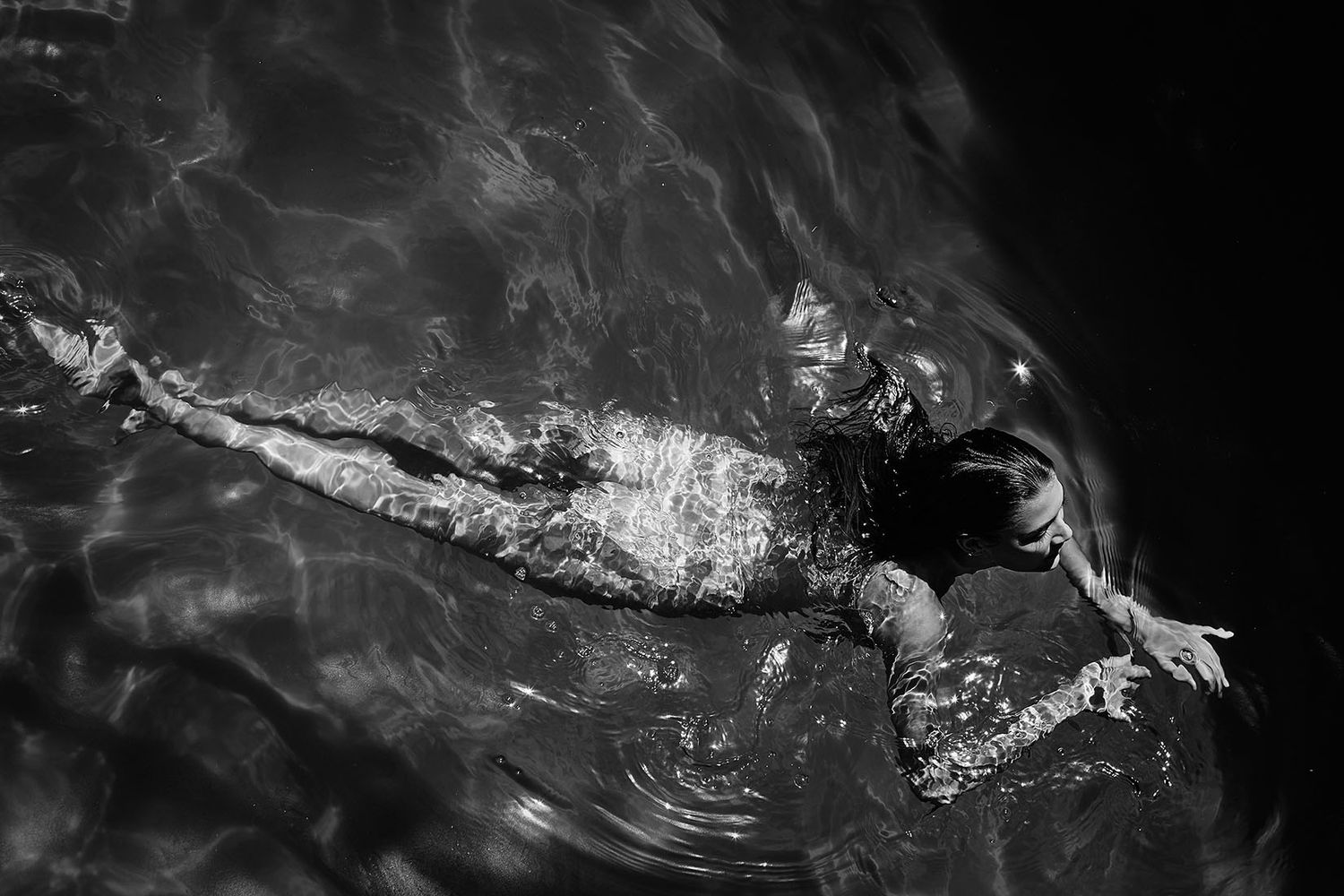 Abstract black and white underwater scene with light reflections and motion blur.