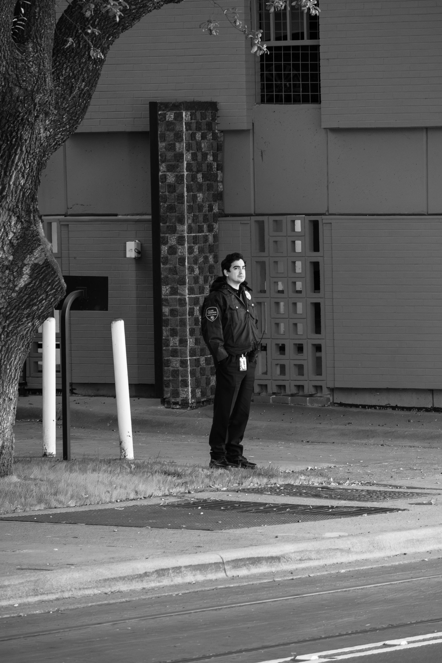 Security guard standing on a sidewalk near a building with brick and concrete walls.