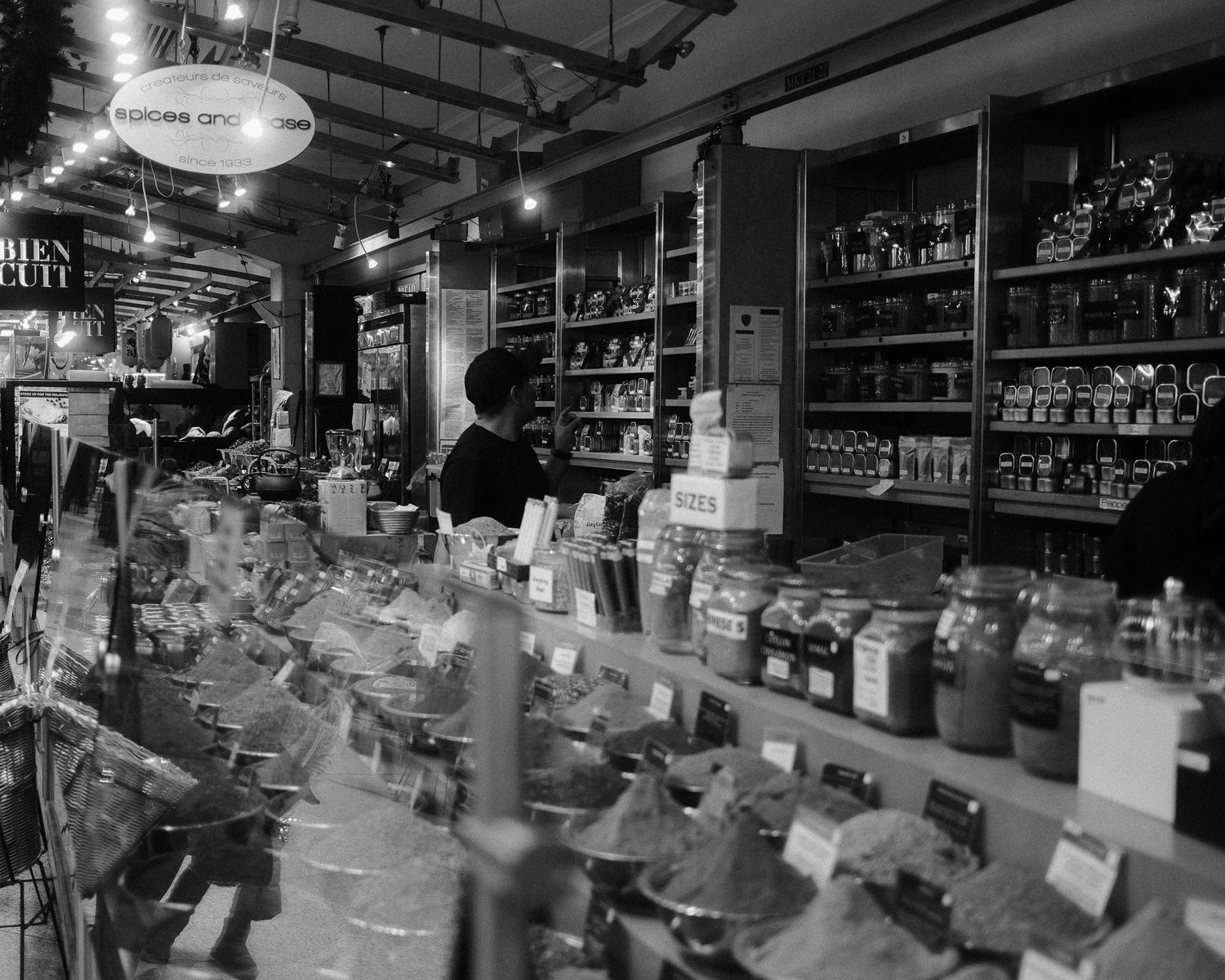 Person arranging items on shelves inside a spice and food market.