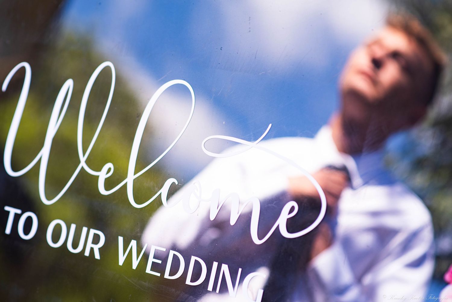 The groom adjusts his tie in a reflection before his bride arrives.