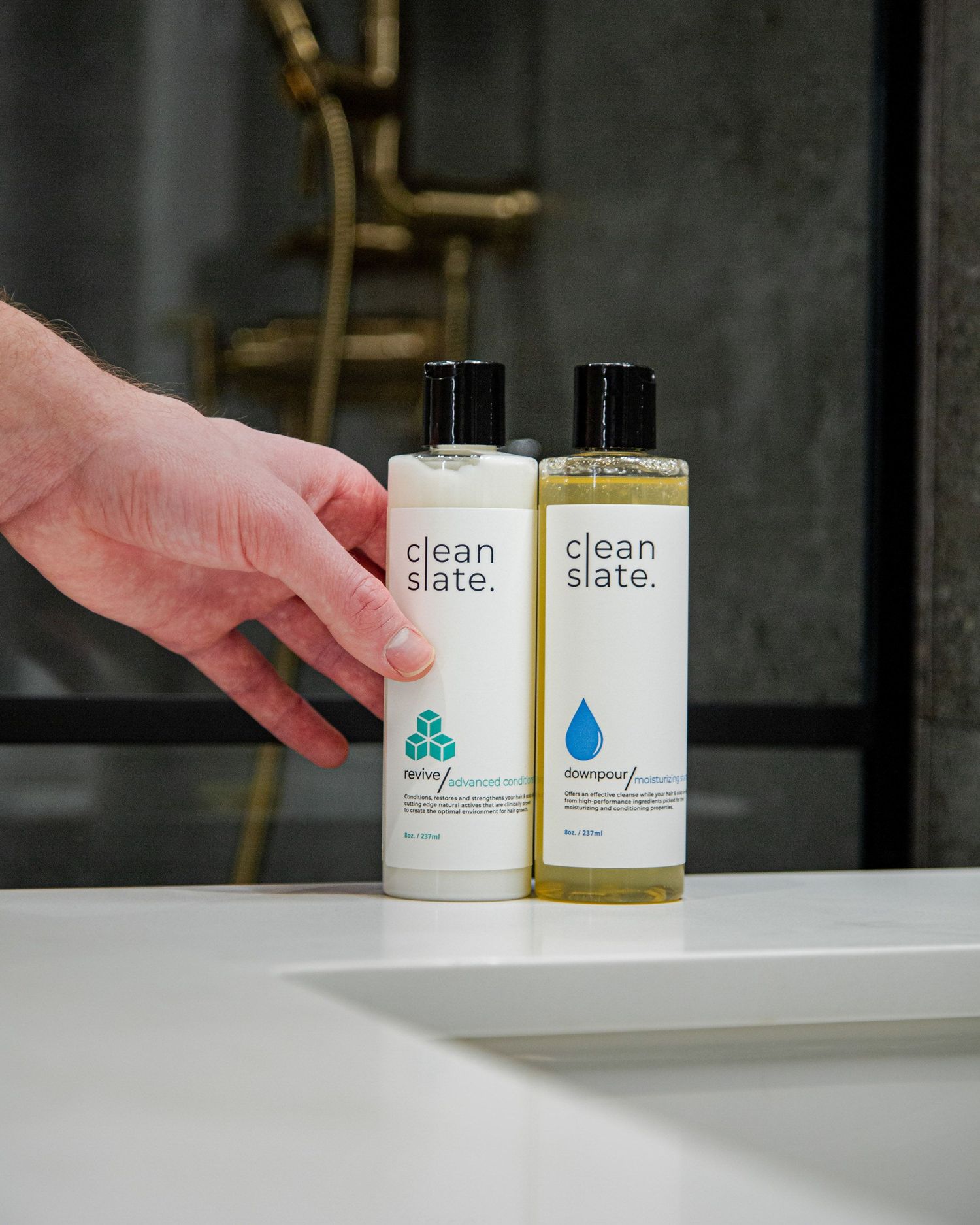 Clean slate beauty products being arranged on white counter surface.