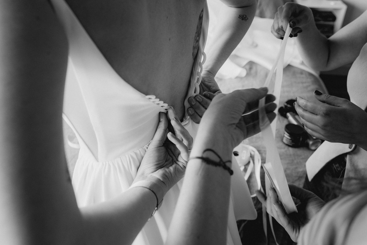 Close-up detail shot of dress adjustments being made during wedding preparations.