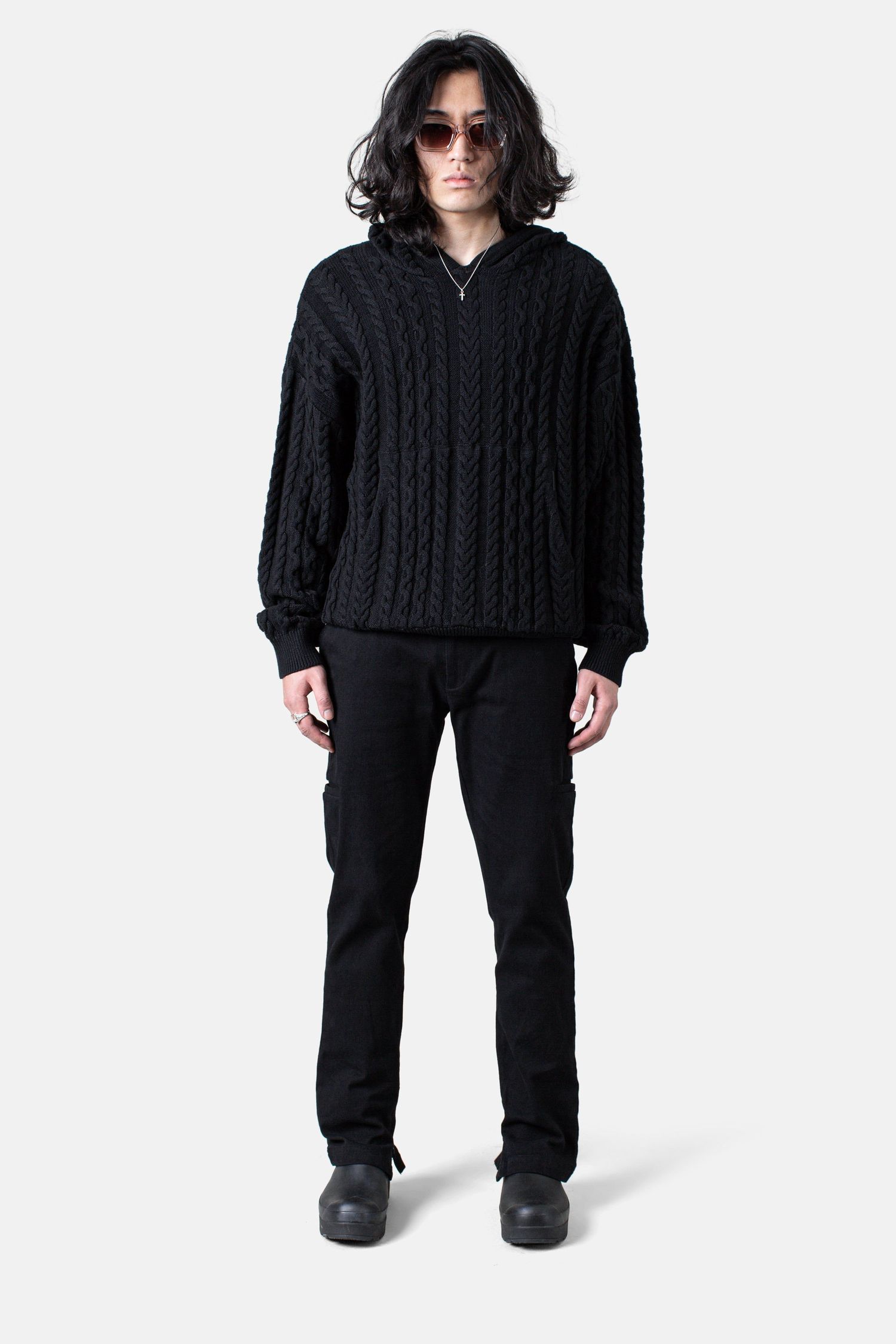 Black cable knit sweater and pants outfit photographed against white background.