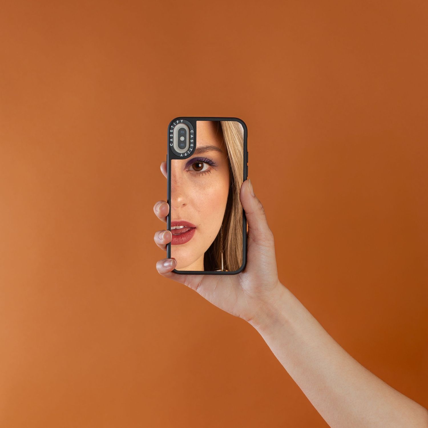 Hand holding smartphone against orange background showing artistic angles.
