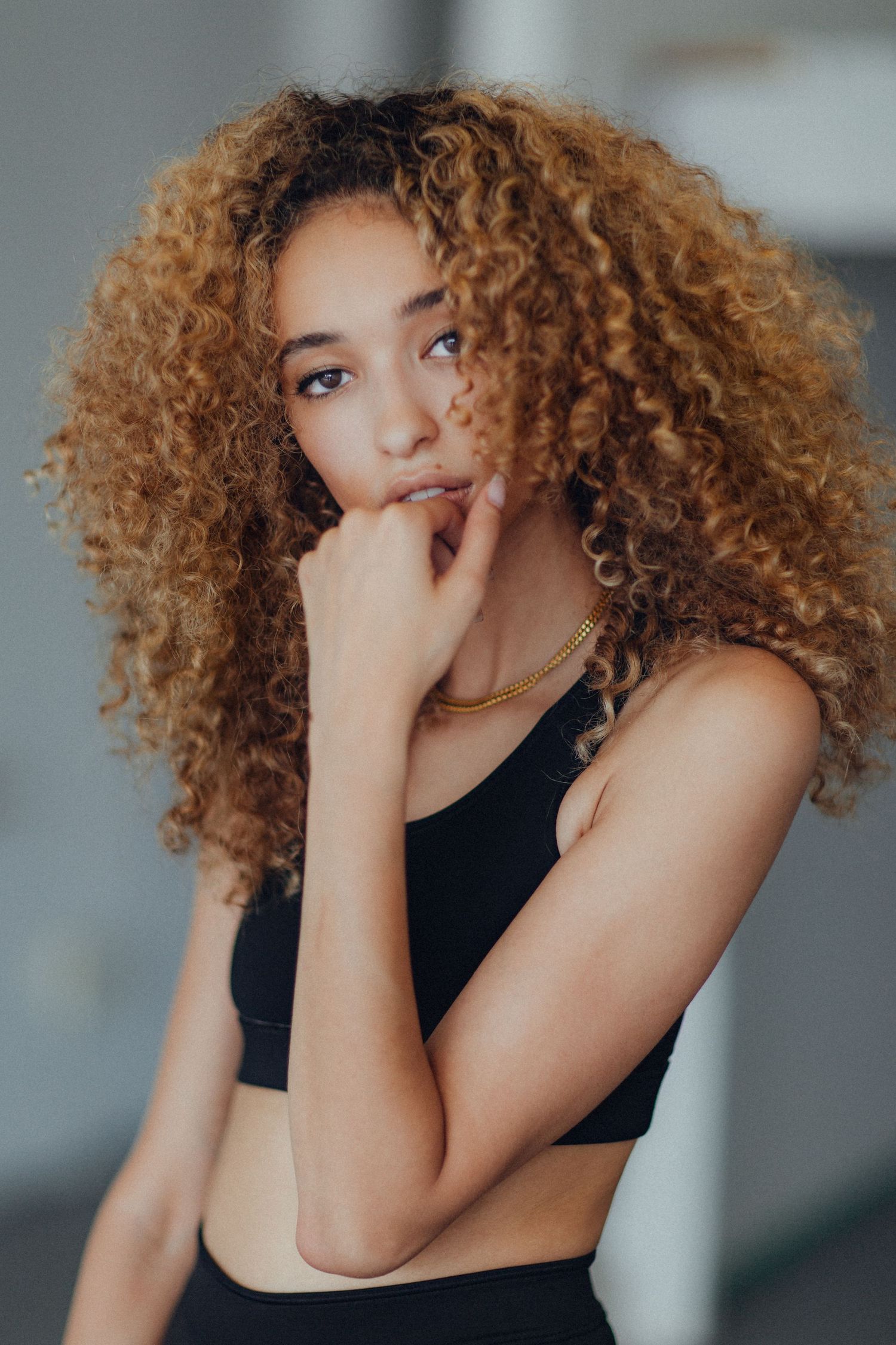 Studio portrait featuring voluminous curly hair and black athletic wear.