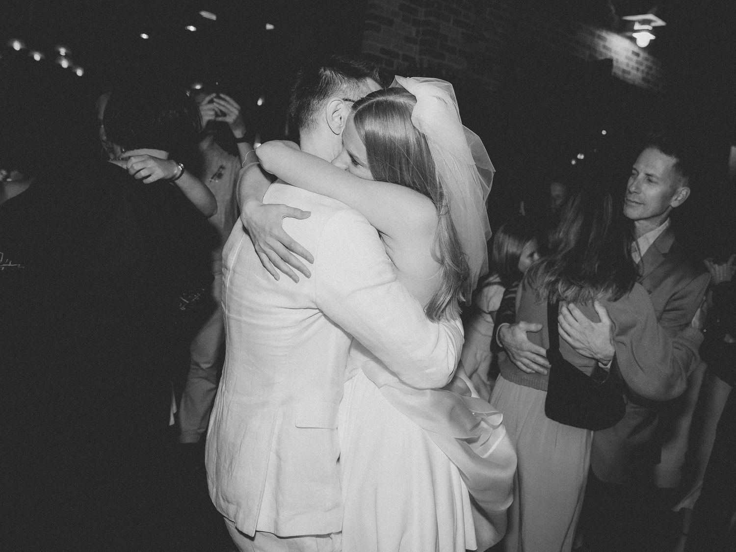Black and white photo of a bride and groom sharing a romantic embrace on the wedding dance floor.