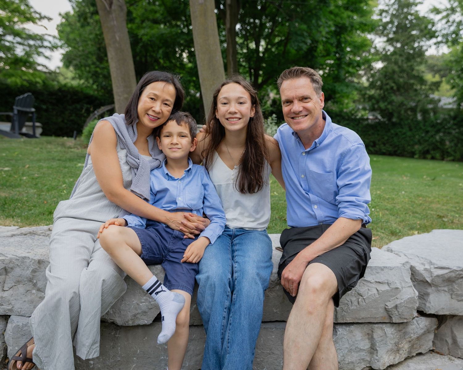 Casual family photos captured on stone blocks in a park setting during summer.