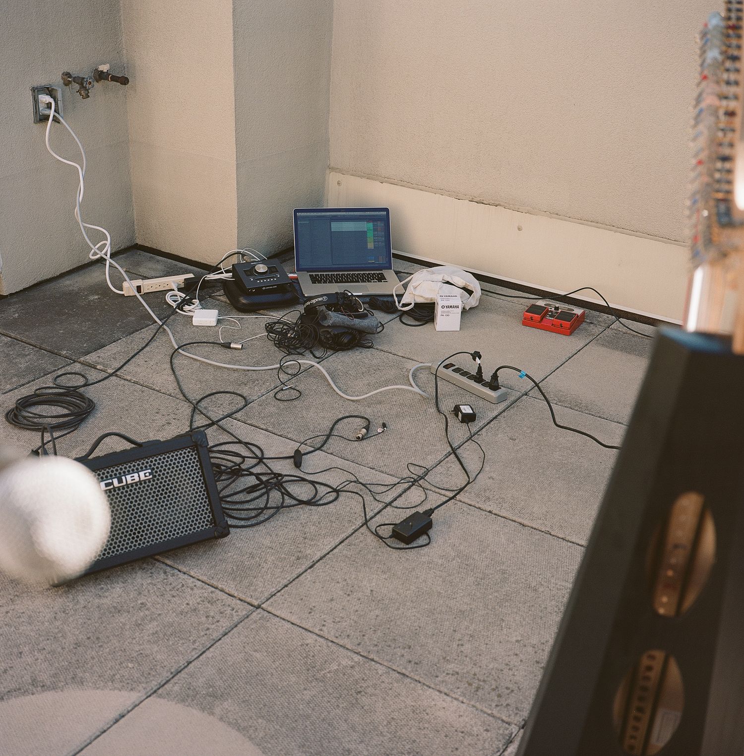 A messy floor setup with laptop, cables and electronic equipment scattered around.