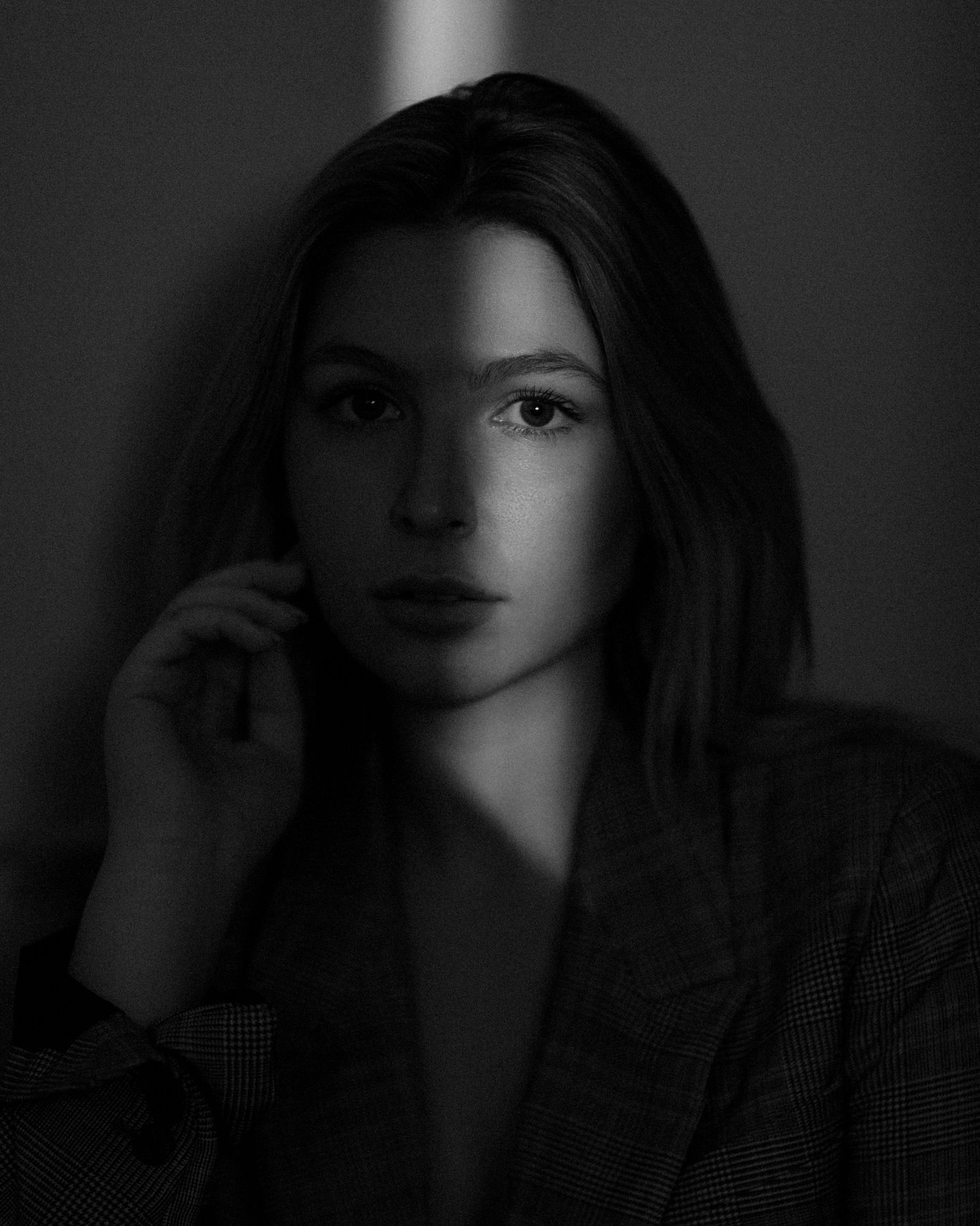 Moody black and white portrait with dramatic shadows and lighting.