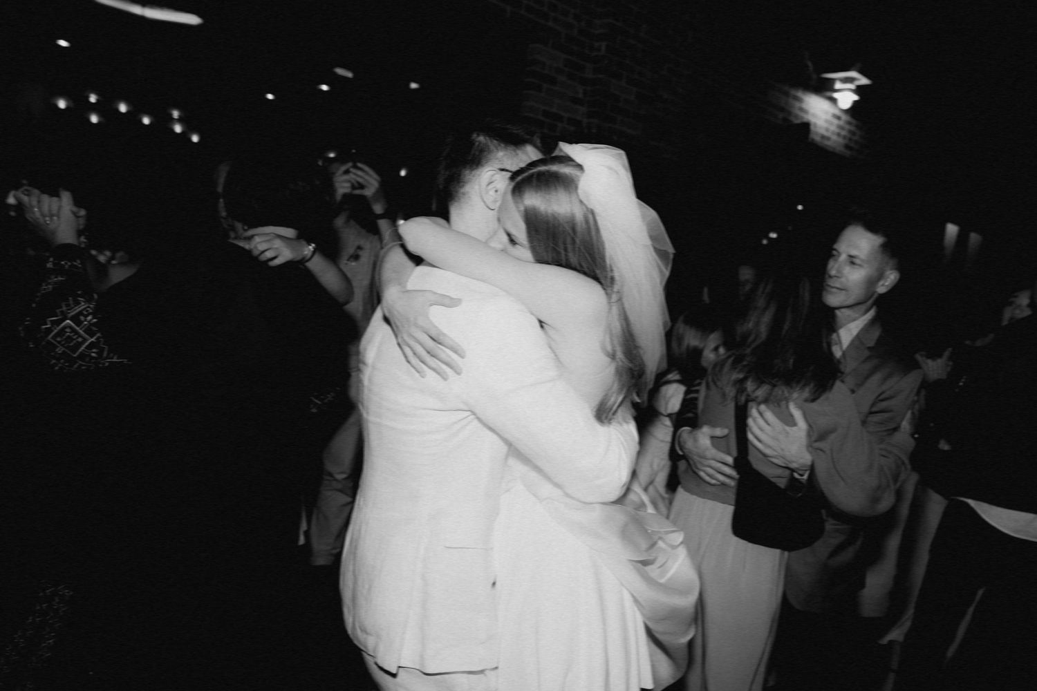 A touching dance floor moment captured in black and white at a wedding celebration.