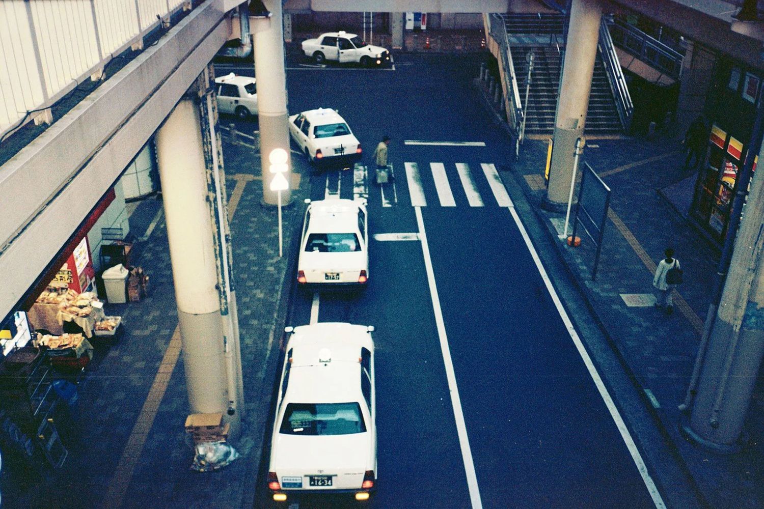 Row of white cars parked along an urban street with buildings.