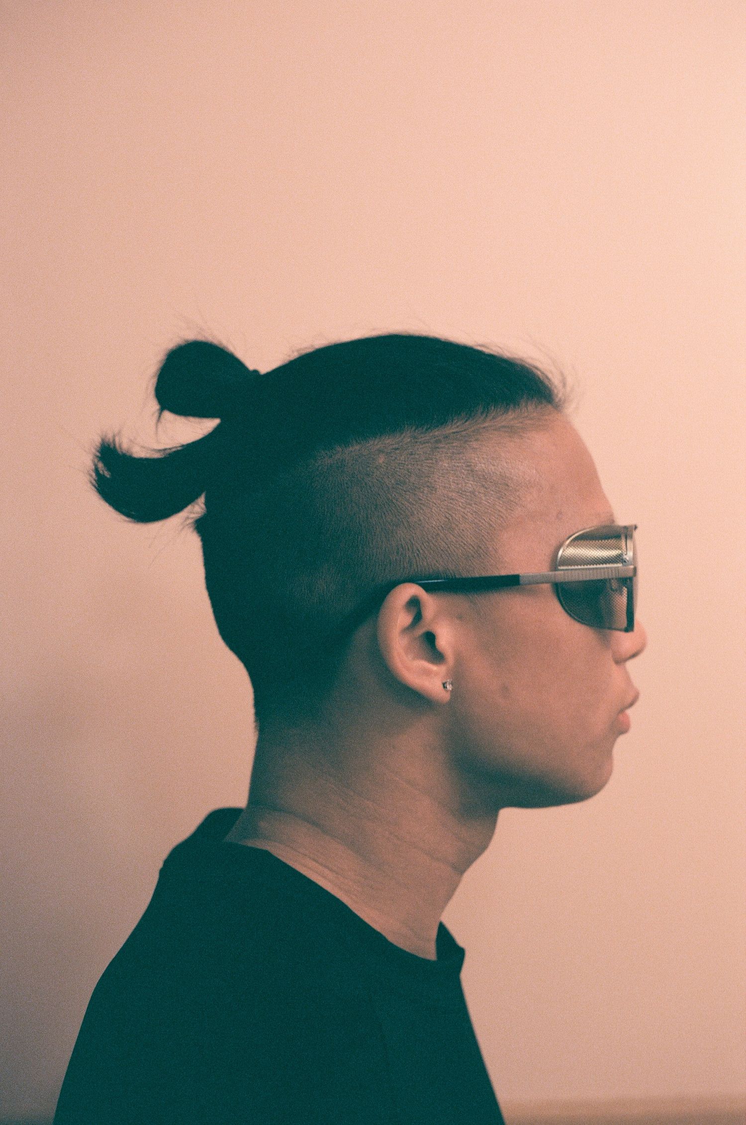 Side profile silhouettes of a person with glasses and hair bun against pink background.