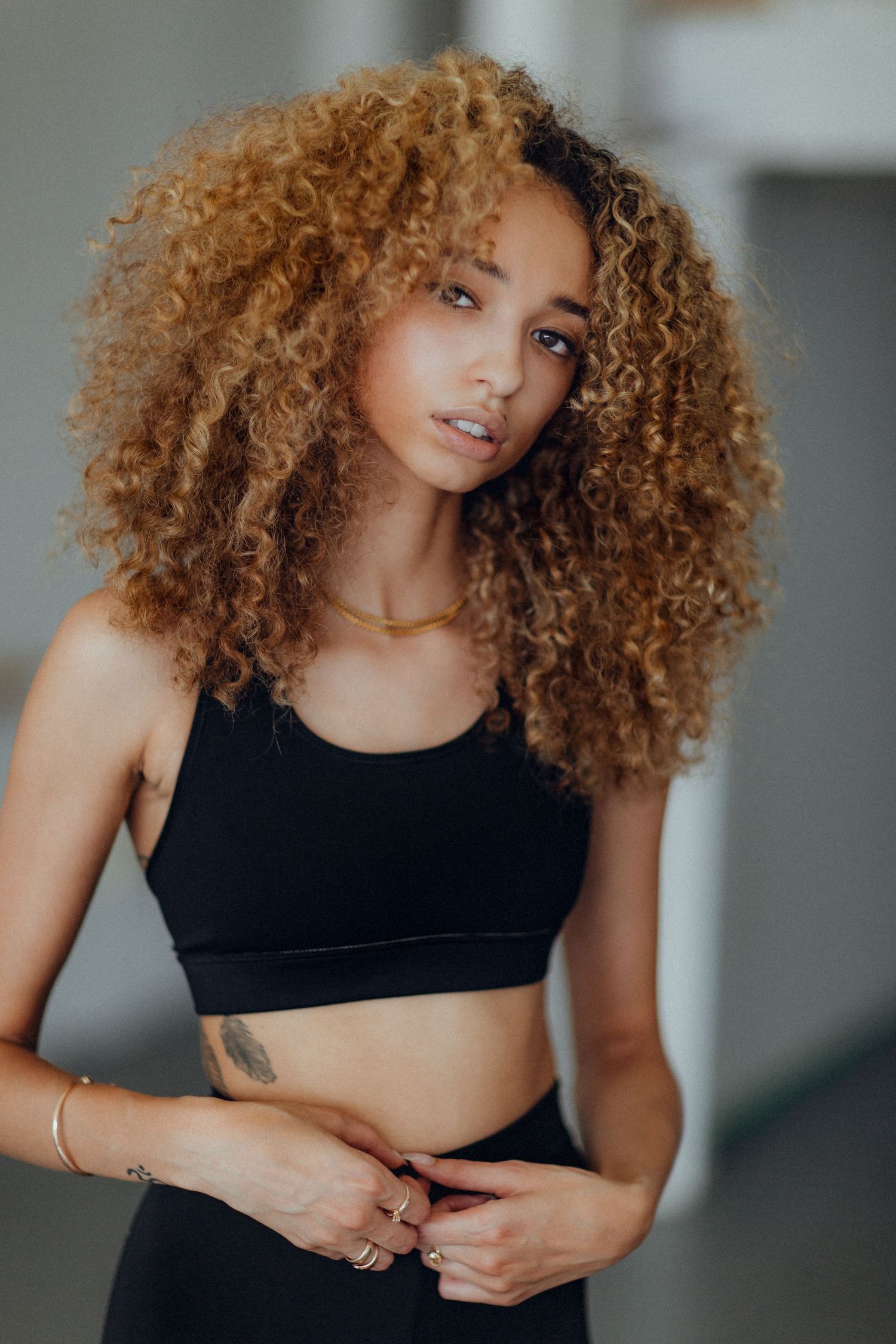 Fashion portrait showcasing natural curly hair and black athletic ensemble.