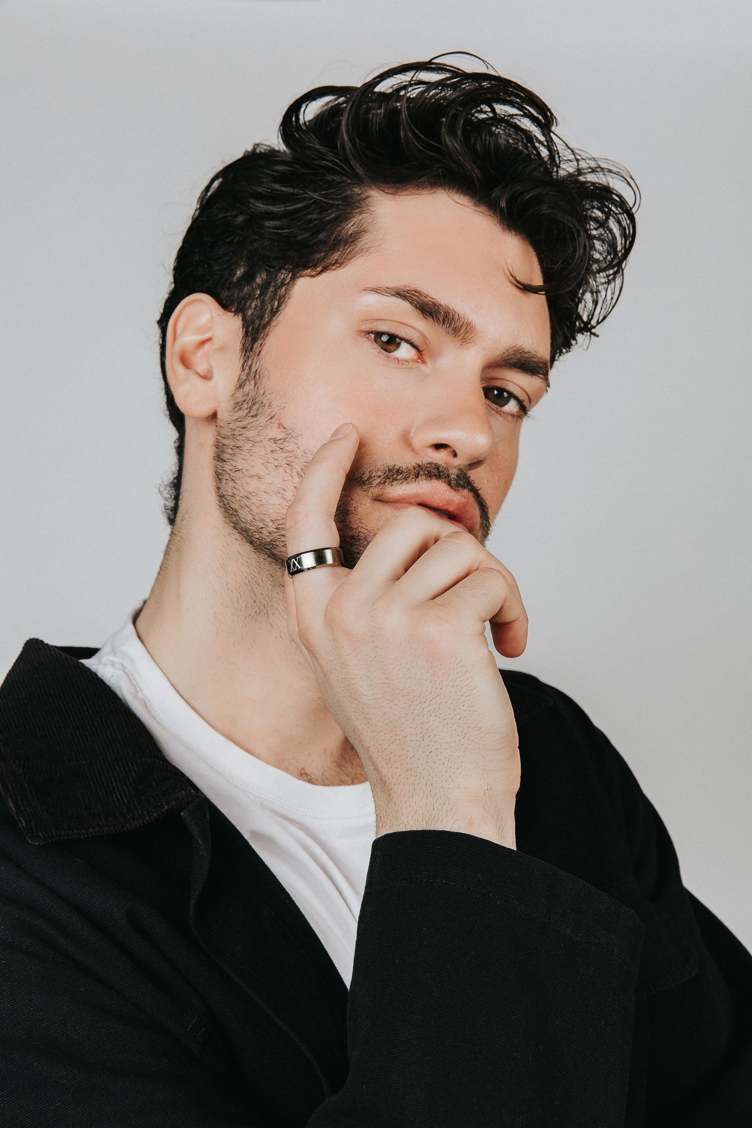 Studio portrait of a person in black turtleneck with thoughtful expression and ring.