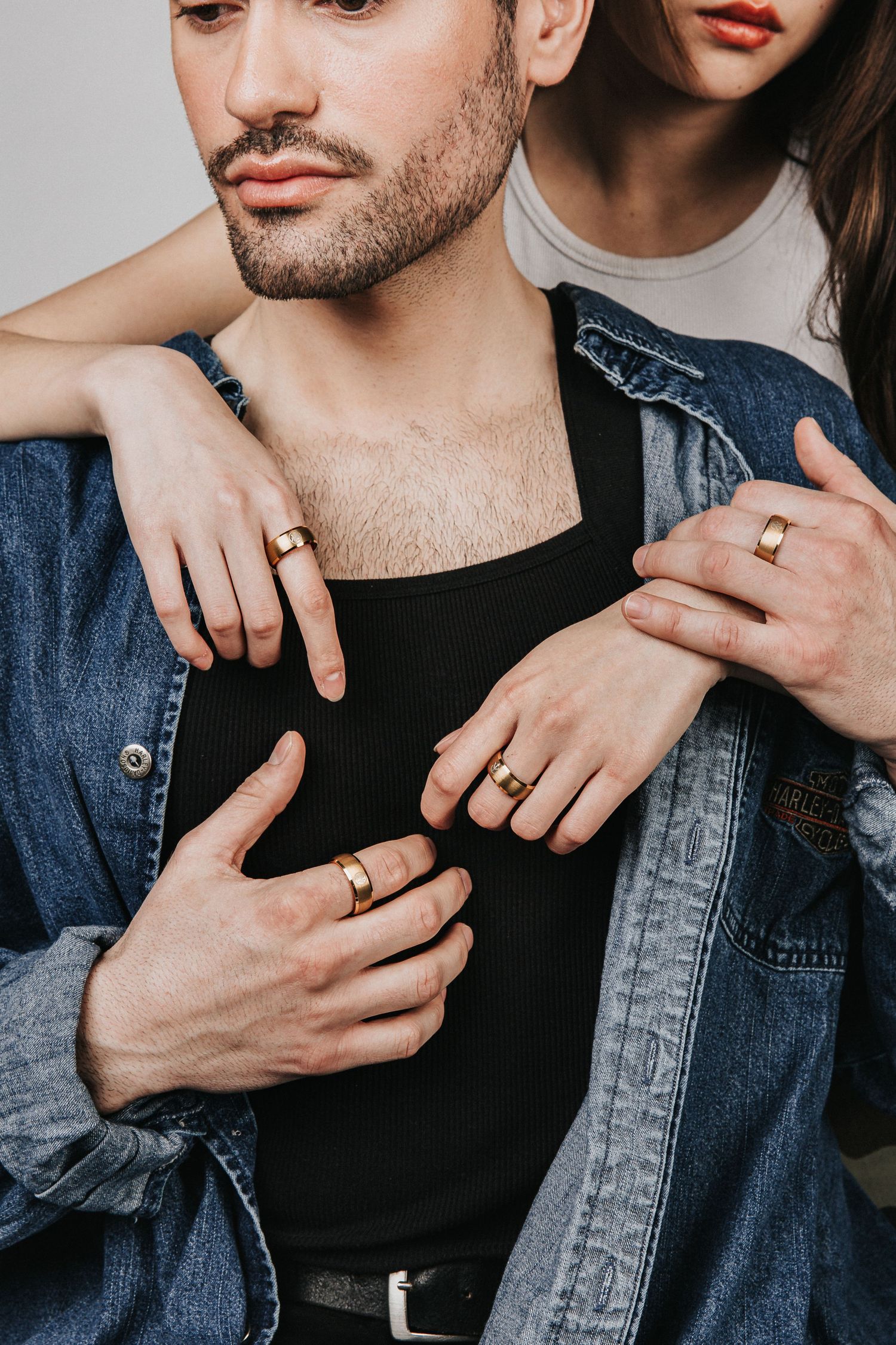 Close-up shots showing hands wearing rings and a denim jacket against a black shirt.
