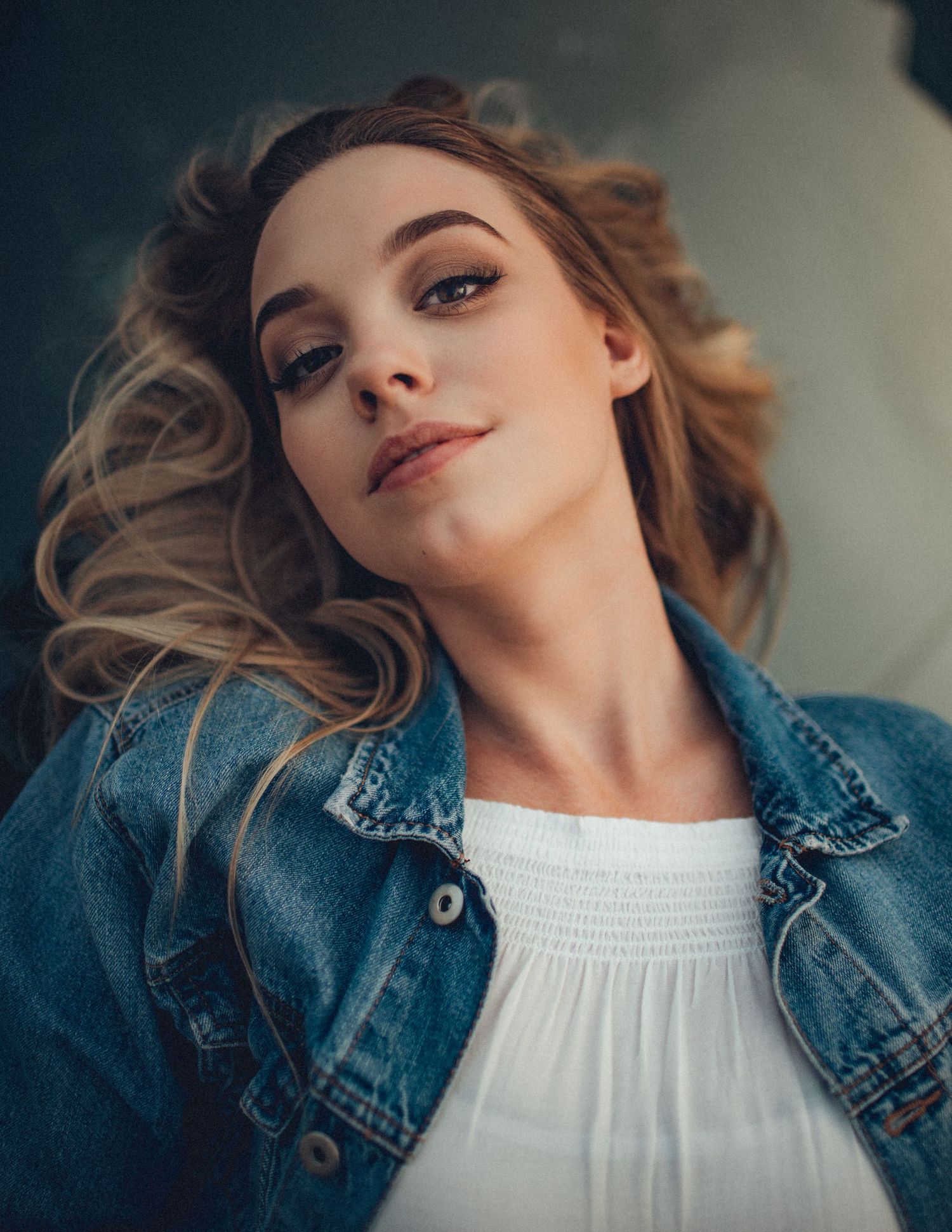 Casual portrait in denim jacket and white top with natural lighting.