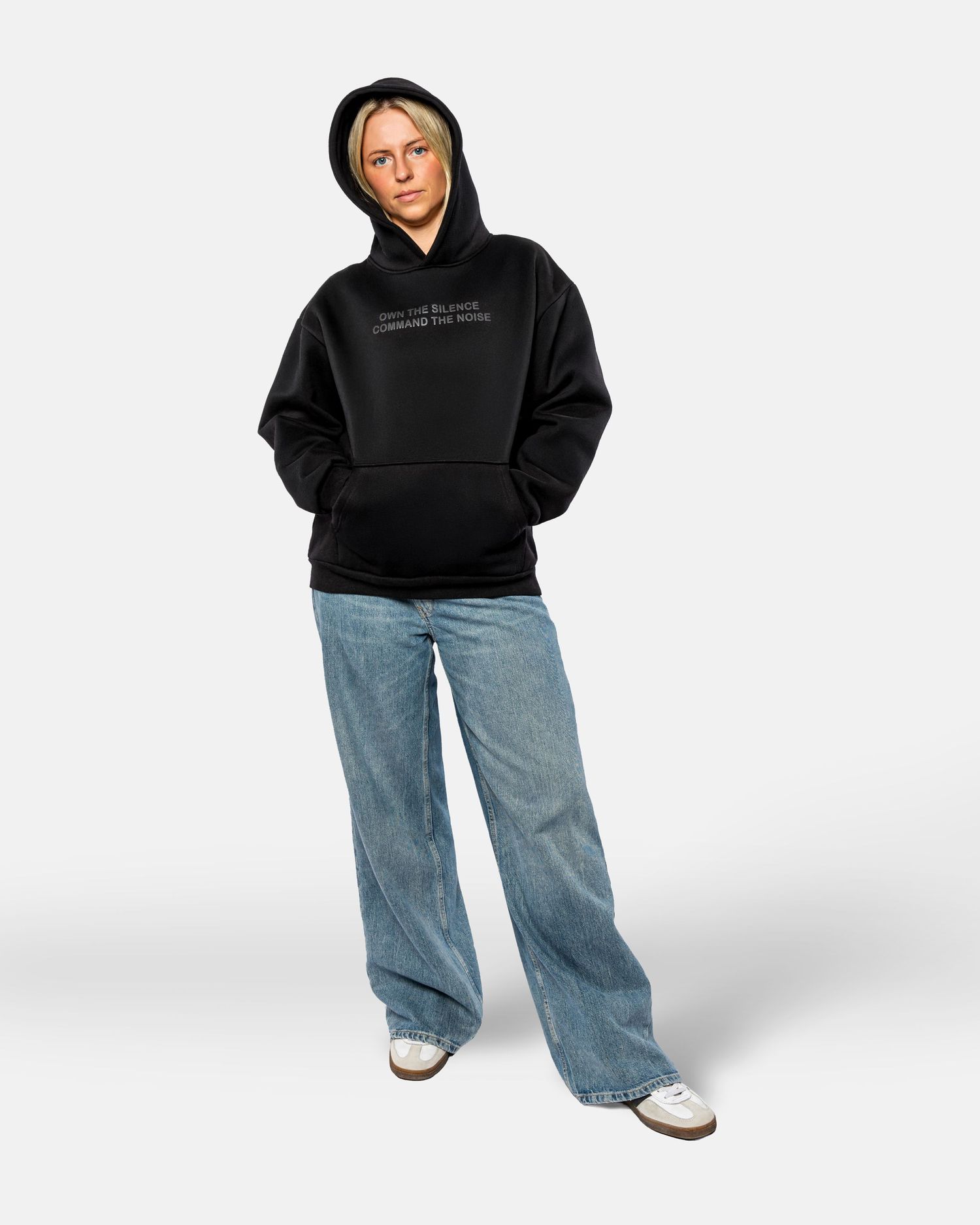 Person wearing a black hoodie and light wash baggy jeans poses against white background in four different angles.