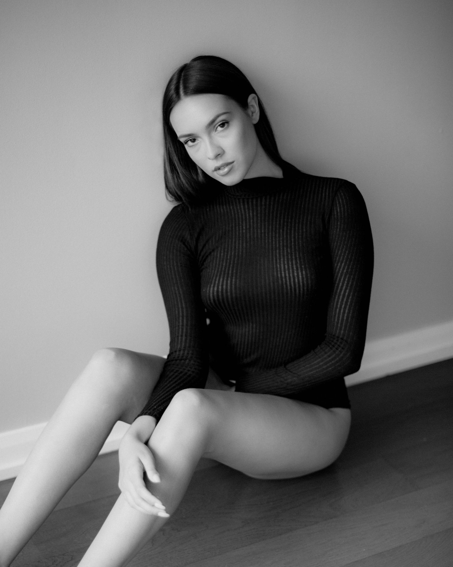 Minimalist black and white portrait series in ribbed sweater against plain wall.