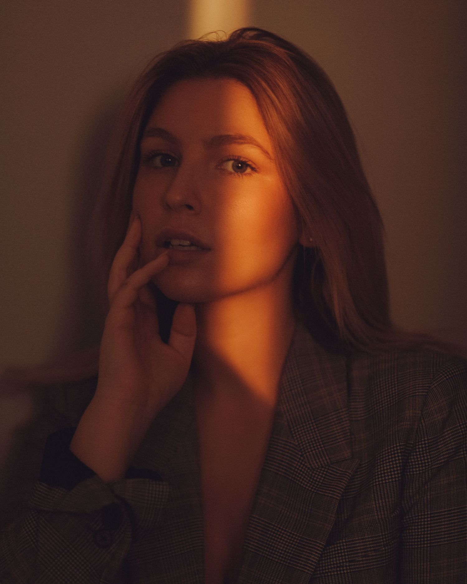 Atmospheric portrait with warm amber lighting creating dramatic shadows.