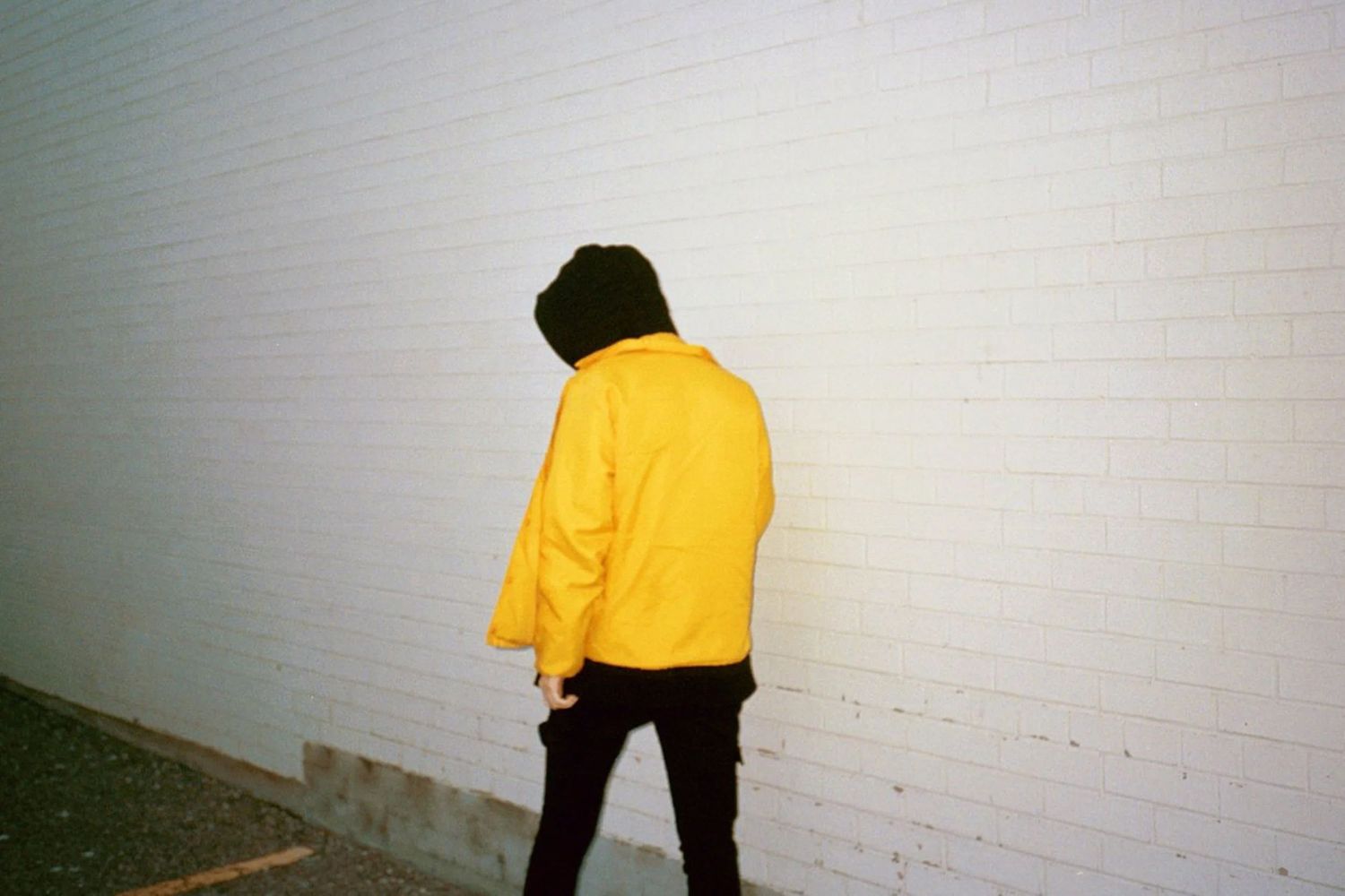 Person wearing a yellow jacket walking down an urban street.