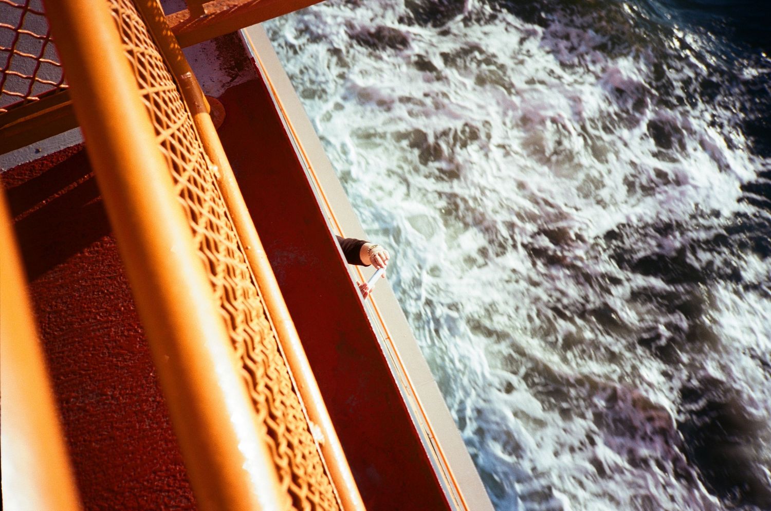 Dramatic ocean waves crashing against a cruise ship railing at sunset.