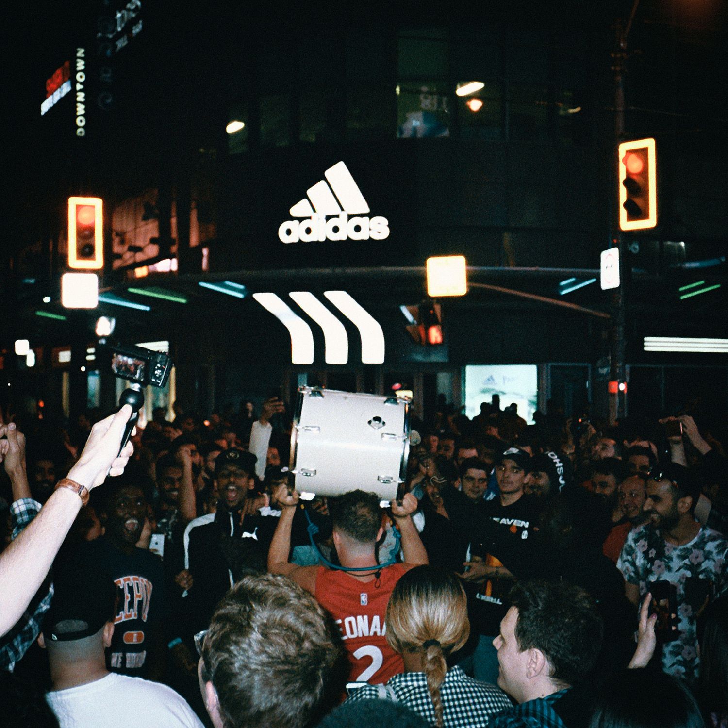 Crowded nightclub scene with Adidas logo visible in neon lighting.