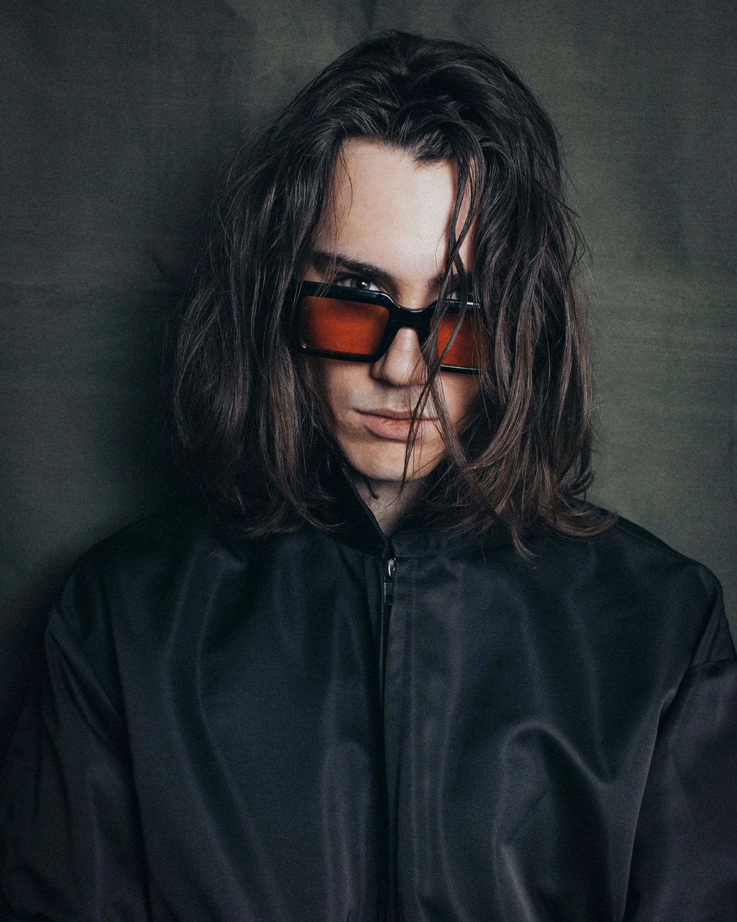 Moody fashion portraits featuring dark clothing and red-tinted sunglasses against grey background.