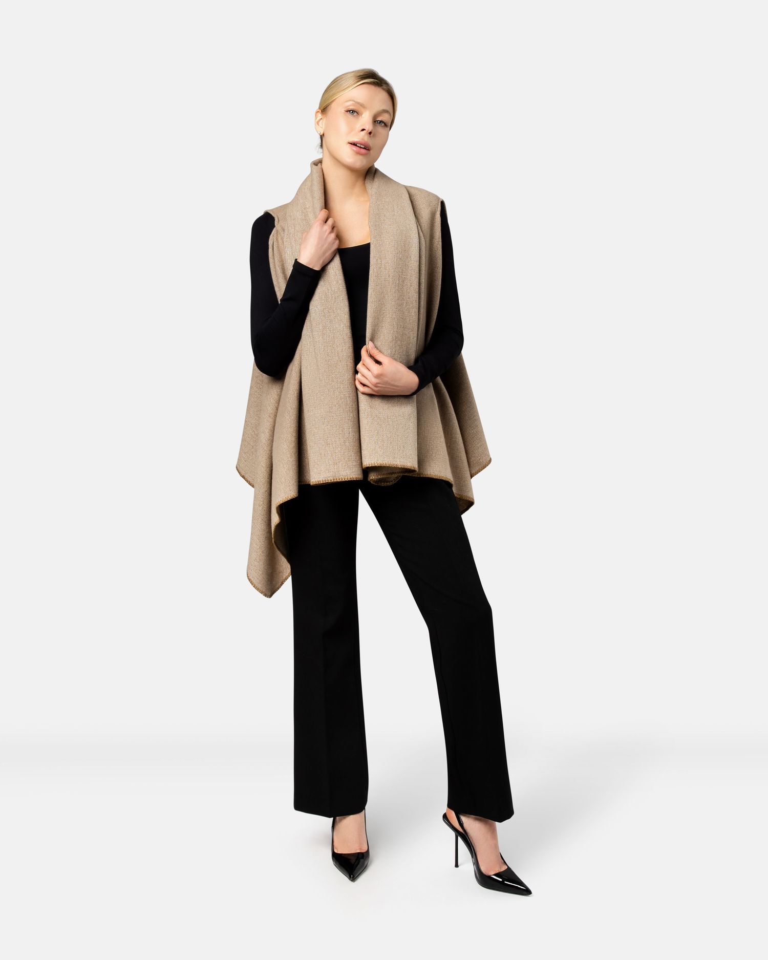 A model wearing a black jumpsuit with a beige draped shawl collar jacket and pointed heels in three different poses.
