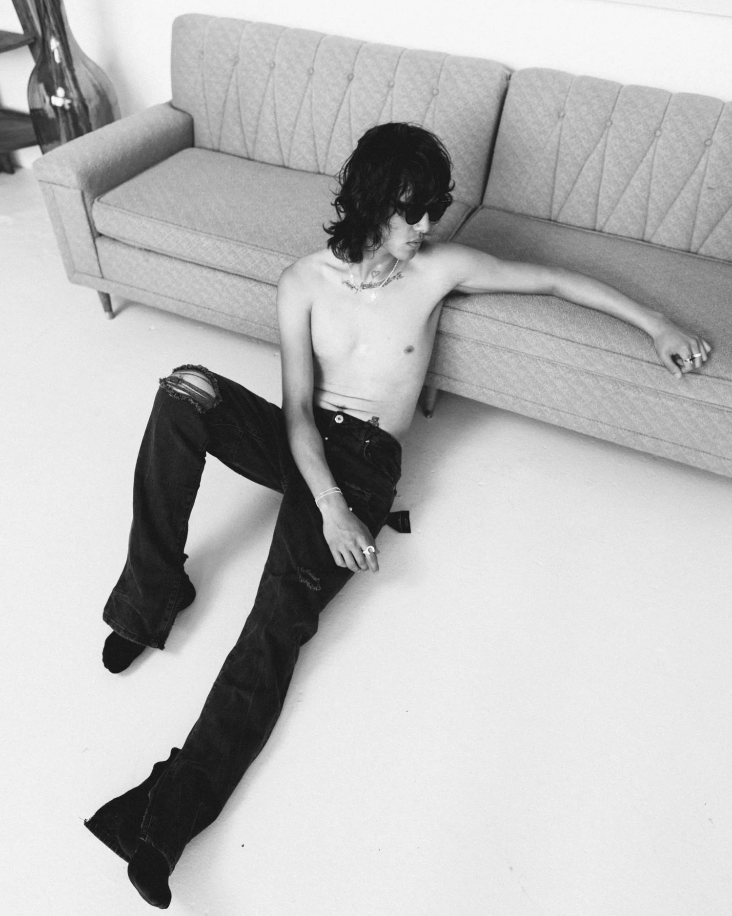 Black and white photo series of relaxed poses on grey couch.