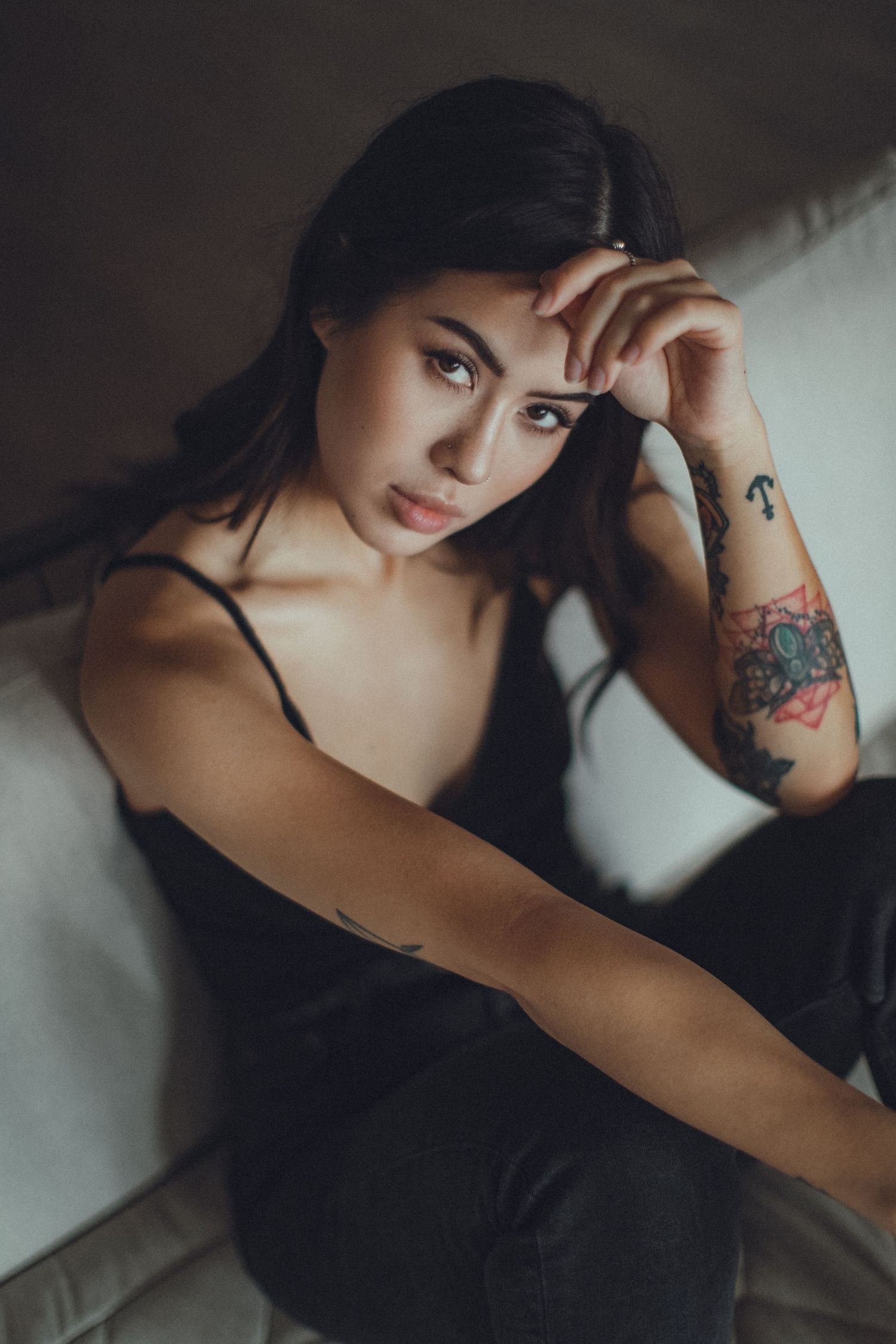 Moody boudoir photoshoot featuring dark clothing and dramatic poses on a couch.