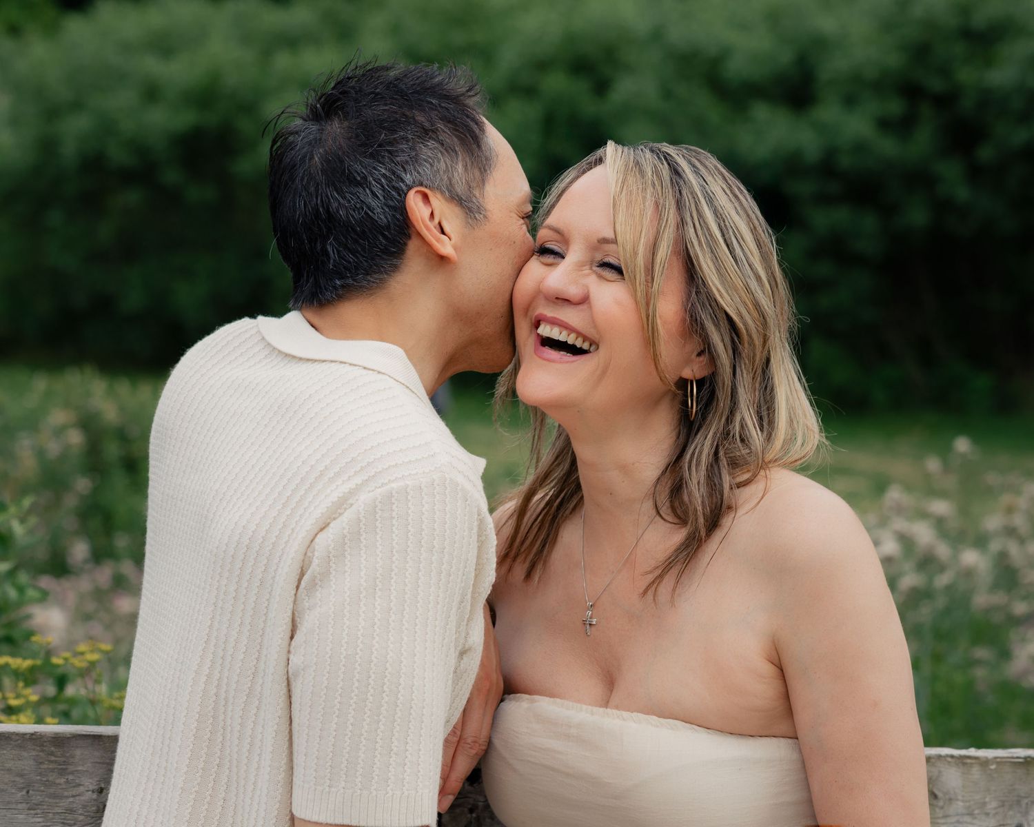 Couple shares intimate moments in outdoor setting with natural greenery.