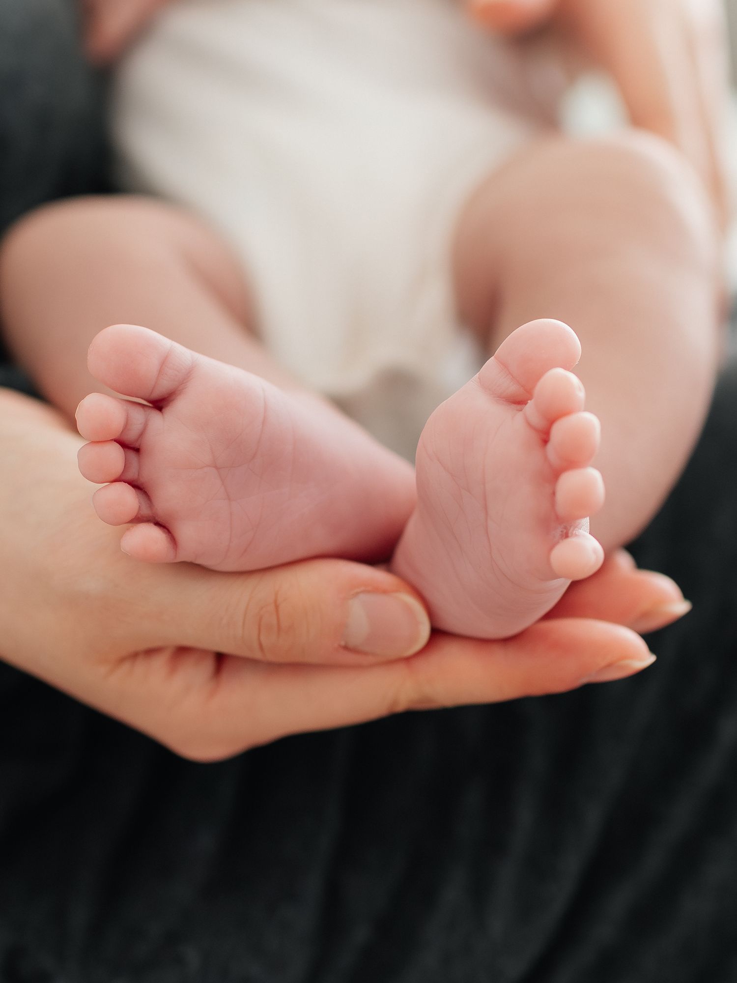 Close-up of a parent cradling tiny newborn baby feet in their hands, a tender moment of new parenthood.