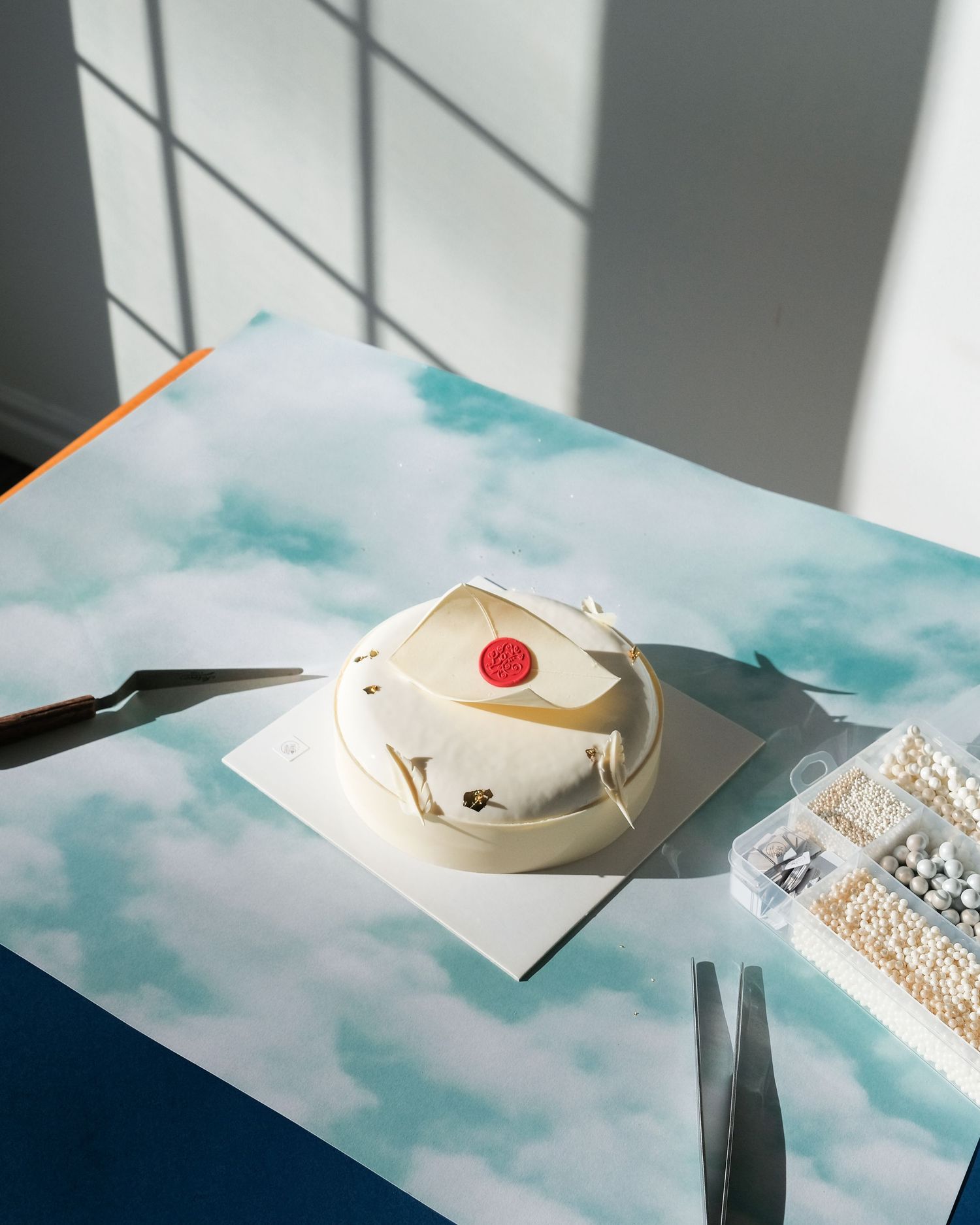 Artistic still life with white paper decorations and beads on a light blue surface.