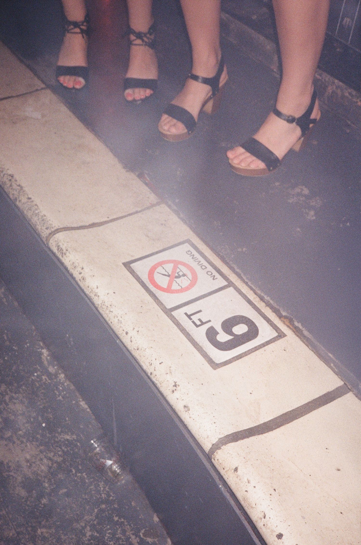 Close-up view of feet walking across numbered floor tiles in a dimly lit space.