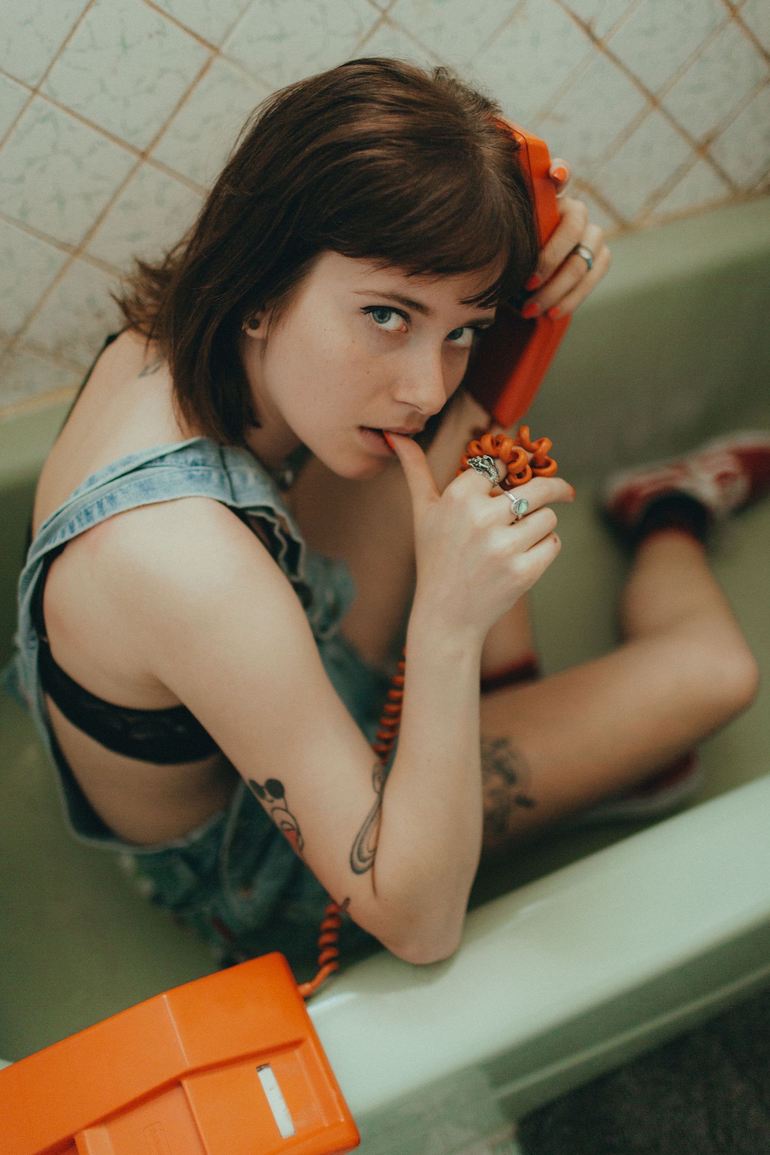 Artistic portrait in denim with orange accents in tiled setting.